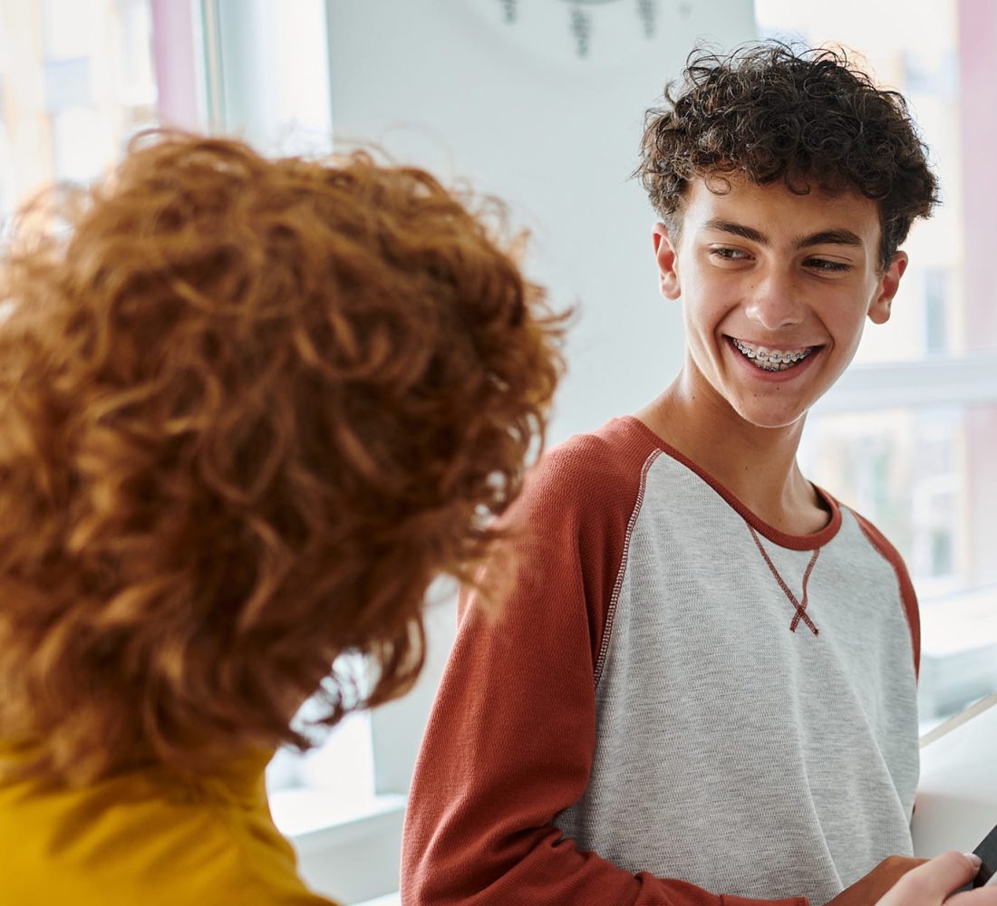 Lächelnder Schüler mit Zahnspange hält ein Notizbuch
